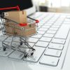 E-commerce. Shopping cart with cardboard boxes on laptop. 3d