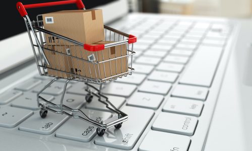 E-commerce. Shopping cart with cardboard boxes on laptop. 3d